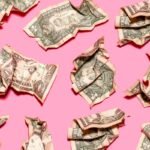 Pattern of crumpled one dollar bills lying against pink background