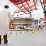 Commonwealth Fusion Systems employees supervise the installation of the tokamak's cryostat base.