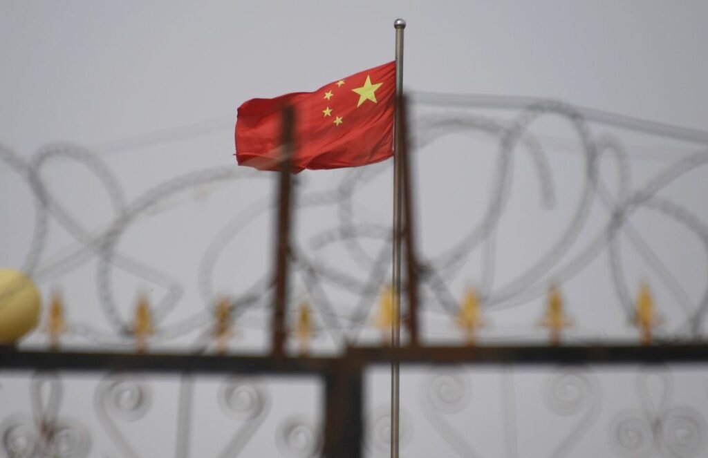 Chinese flag on pole behind razor wire