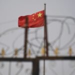 Chinese flag on pole behind razor wire