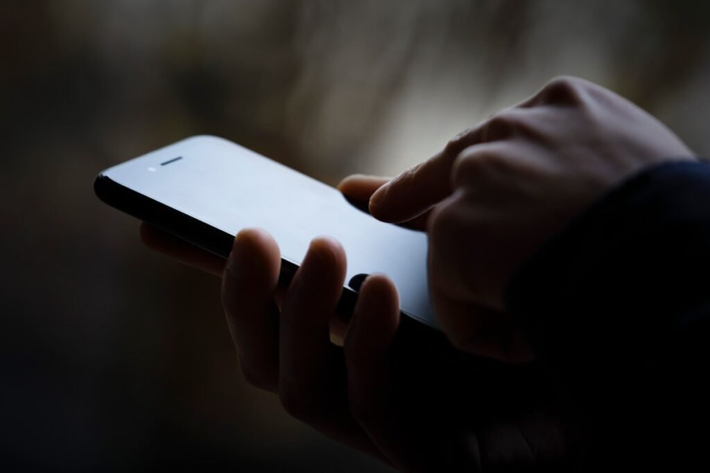 a photo of a person's phone in someone's hand, the image is darkened