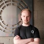 Durin founder Ted Feldmann stands before metal art.