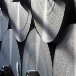 Large rolls of fresh paper sit stacked in a warehouse.