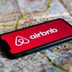 Airbnb logo displayed on a phone screen laying on a map of Krakow