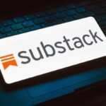 The Substack logo displayed on a phone that is resting on top of a keyboard