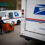 a postal worker worker pushes a mail cart outside a United States Postal Service (USPS) distribution center in Chicago.