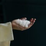 A hand holds white fibers.