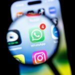 in this photo illustration, the Whatsapp app logo can be seen through a magnifying glass on the display of a smartphone.