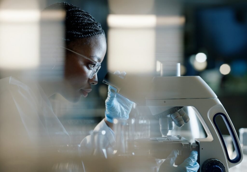 Scientist, microscope and analysis in lab for healthcare and drug discovery