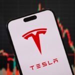 In this photo illustration, the Tesla logo is displayed on a smartphone screen