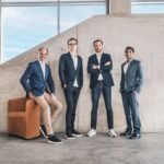 Four men standing in front of a concrete wall.