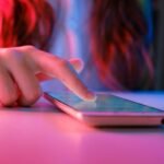 person touching a smartphone laying on a table.