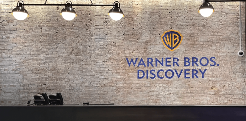 Warner Bros. Discovery logo on a brick wall