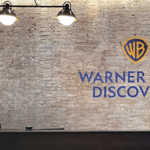 Warner Bros. Discovery logo on a brick wall