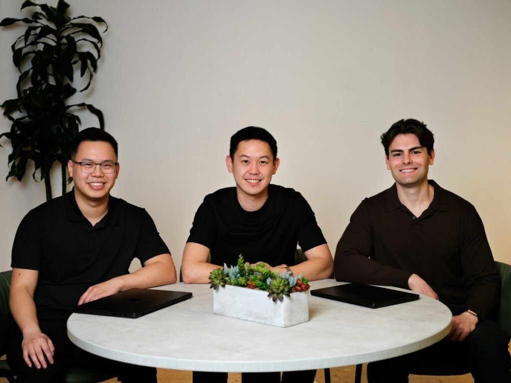 Three men in black shirts sit around a circular table