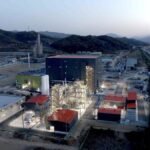 A battery materials factory is lit up at dusk.