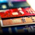 Close up macro color image depicting an abstract view of a collection of debit and credit cards and numeric digits.