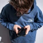 Shows a 14-year-old boy as he looks at social media on his mobile phone.