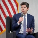 Sam Altman, CEO of OpenAI, sitting in front of American flag