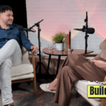 Two people seated in armchairs during a podcast interview, speaking into microphones across a small table with water glasses and a plant, with a “TechCrunch Build Mode” logo overlay in the corner.