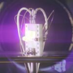 A radiovoltaic material glows under bombardment by alpha particles.