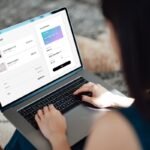 Above the shoulder view of a young Asian woman shopping clothes online on laptop, making payment with credit card. Enjoying seasonal sales. Shopaholic concept. Cyber security idea. Close up shot. Laptop screen mockup.