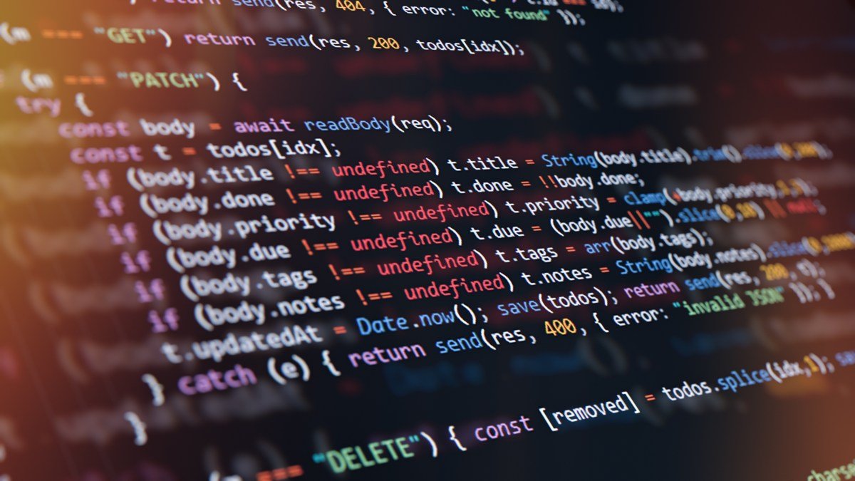 Close-up of computer screen showing colorful programming code lines with syntax highlighting and blurred light reflections.