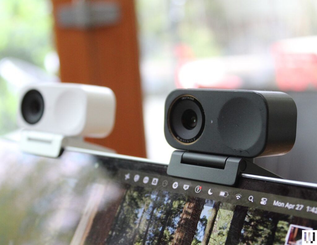 Duas pequenas webcams retangulares presas na parte superior da tela de um laptop, uma branca e outra preta