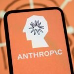 The Anthropic logo is displayed on the screen of a smartphone with the company's branding in the background.