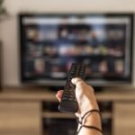 hand holding remote pointed at TV