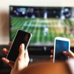 Friends using mobile phone during a tennis match on the TV.